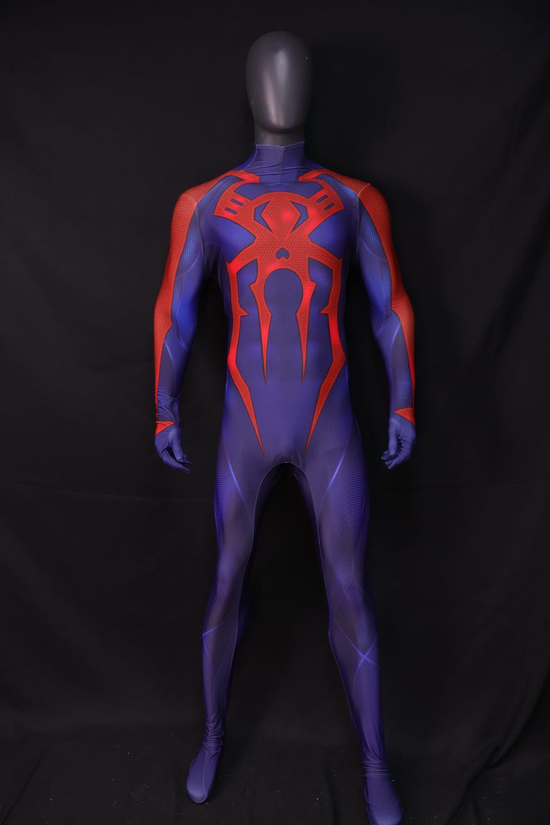 May include: A full-body costume in blue with red accents, displayed on a mannequin. The costume features a red spider emblem on the chest and back, with red detailing on the arms. The suit is form-fitting and covers the entire body.