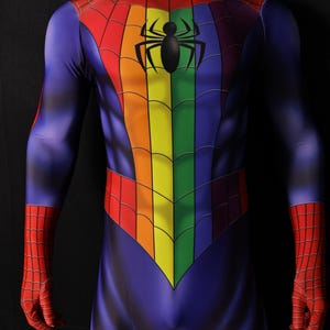Puede incluir: Un disfraz de superhéroe de cuerpo entero en tonos de azul, rojo, naranja, amarillo y verde. El pecho presenta un diseño de arcoíris con un emblema de araña negra. El disfraz tiene guantes rojos con telarañas y un patrón de telaraña roja en los hombros.
