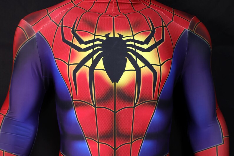 Puede incluir: Un disfraz de Spider-Man rojo, azul y negro. El disfraz presenta un gran emblema de ara&ntilde;a negra en el pecho y la espalda, con un fondo amarillo. El traje tiene un dise&ntilde;o de telara&ntilde;a.