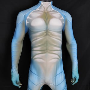 Może przedstawiać: Pełny kostium w kolorze niebiesko-białym, prezentowany na manekinie. Projekt obejmuje wysoki dekolt i szczegółowy nadruk imitujący muskulaturę. Rękawy i nogawki są długie, co daje futurystyczny wygląd.