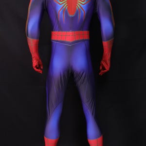 Puede incluir: Un disfraz de superh&eacute;roe de cuerpo entero en azul, rojo y negro. El disfraz presenta un emblema de ara&ntilde;a roja en la espalda y detalles rojos en los hombros, guantes y botas. El traje es ajustado y parece estar hecho de un material el&aacute;stico.