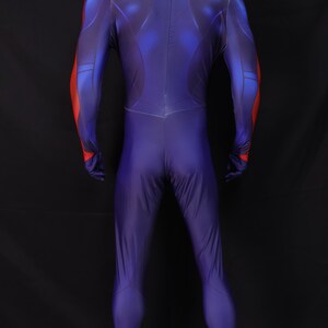 May include: A full-body, form-fitting costume in shades of blue and red. The suit has a high collar and covers the entire body, including the hands. Red accents are on the shoulders and arms. The back of the suit is visible.