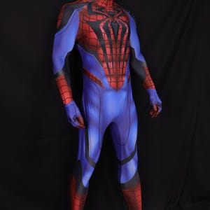 May include: A full-body superhero costume in blue, red, and black, displayed on a mannequin. The costume features a spiderweb design on the chest and a mask that covers the entire head. The suit has a form-fitting design.