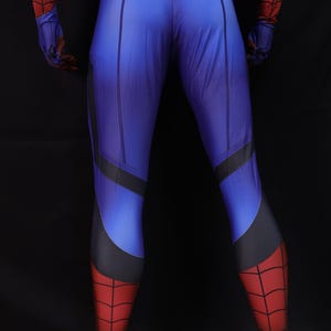 May include: Blue and red superhero costume with a textured pattern. The costume features a blue torso and legs with black accents, transitioning to red legs and feet. The gloves and upper arms are red and black.