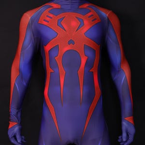 May include: A full-body superhero costume in shades of blue and red. The suit features a large red spider emblem on the chest and red accents on the arms and legs. The costume is displayed on a mannequin.