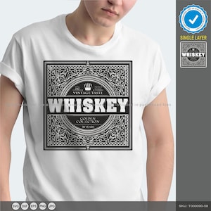 Pode incluir: Uma camiseta branca com um design gráfico preto e branco de um rótulo de uísque vintage. O rótulo apresenta detalhes ornamentados, uma coroa e o texto "WHISKEY, Vintage Taste, Golden Collection, 58 Years".