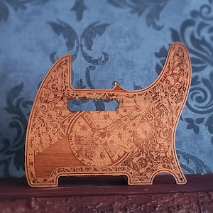 Könnte beinhalten: Ein hellbraunes Gitarren-Schlagbrett aus Holz mit filigranen Lasergravuren und einer detaillierten Darstellung des Millennium Falcon Raumschiffs aus Star Wars, inklusive rechteckigem Ausschnitt und vorgebohrten Montagelöchern.