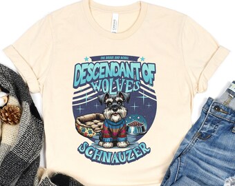 May include: Cream-colored t-shirt featuring a Schnauzer dog graphic with the text "Descendant of Wolves Schnauzer." The shirt is paired with denim shorts and a black and gray plaid scarf with decorative elements.