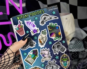 May include: A sticker sheet titled Witchy Oddities featuring various illustrations including a potted plant with crystals, a purple hand, a bird skull, a space scene, a cat skull with a rose, a spellbook, and a hand holding a banner with small teal stars.