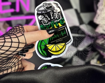 Puede incluir: Una pegatina con un diseño de lata de refresco de dibujos animados con dos figuras de esqueleto. La lata está etiquetada como "Sprite" y "Hater-Aid" con un gráfico de limón y rodaja de lima. El texto dice "porque nada alimenta el éxito como su envidia."