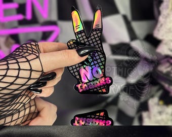 May include: A holographic sticker in the shape of a peace sign with the words "No Thanks" in a colorful, bubble-style font. The sticker is held by a hand wearing a black fishnet glove and black nail polish. A second sticker with the word "Thanks?" is also visible.