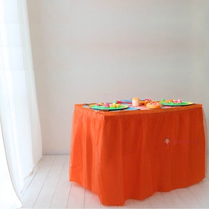Può includere: Gonna da tavolo arancione con un bordo arricciato. La gonna è realizzata in tulle ed è perfetta per aggiungere un tocco di eleganza a qualsiasi tavolo.