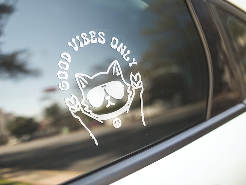 May include: White vinyl sticker with a cartoon cat wearing sunglasses and peace signs, with the text "Good Vibes Only" around the cat.