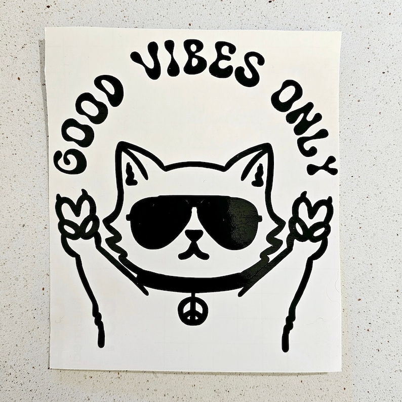 May include: Black and white sticker with a cartoon cat wearing sunglasses and a peace sign necklace. The cat is holding up two peace signs. The text "GOOD VIBES ONLY" is written in a circle around the cat.