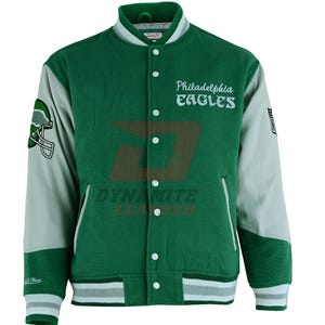 May include: Green and grey Philadelphia Eagles letterman jacket. The jacket has the team name and logo on the front, with white accents on the collar, cuffs, and hem. The sleeves are grey, and the jacket has a button-up closure.