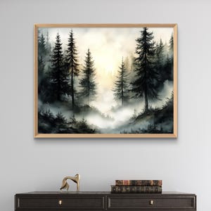 May include: Watercolor painting of a misty forest scene. Tall, dark evergreen trees dominate the foreground, with a soft, golden light filtering through the fog in the background. The artwork is framed in a light wood frame.