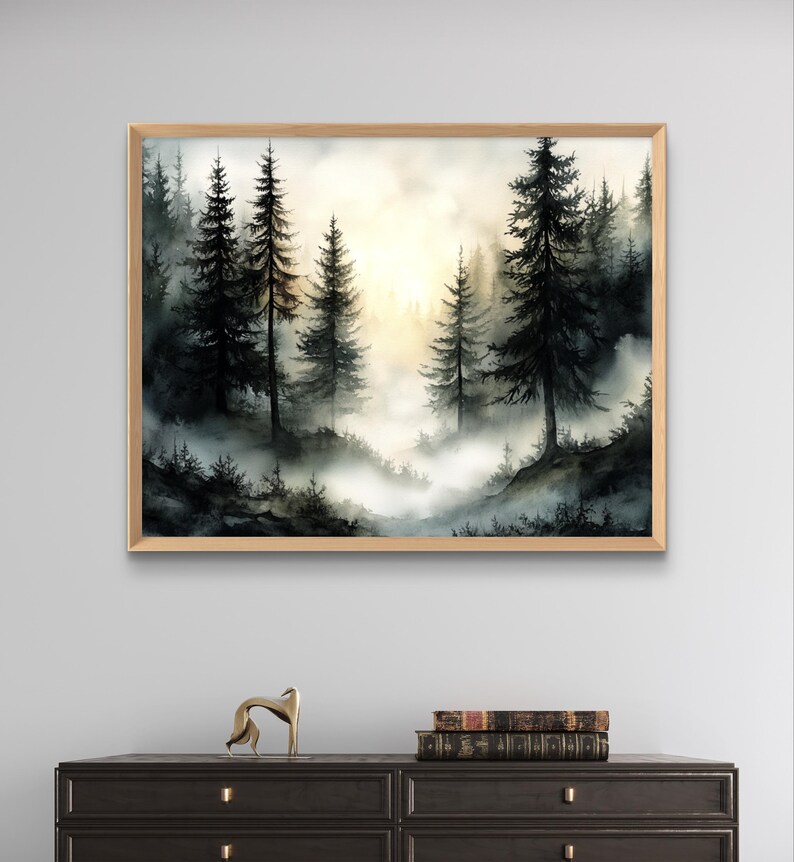 May include: Watercolor painting of a misty forest scene. Tall, dark evergreen trees dominate the foreground, with a soft, golden light filtering through the fog in the background. The artwork is framed in a light wood frame.