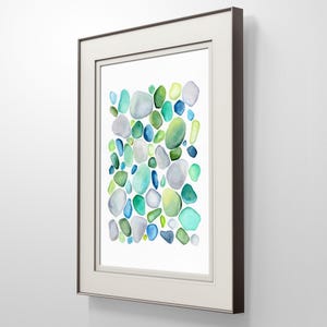 Puede incluir: Una impresi&oacute;n en acuarela enmarcada con un dise&ntilde;o abstracto de formas redondeadas y coloridas. La obra de arte presenta una paleta de azules, verdes y grises, sobre un fondo blanco. El marco es marr&oacute;n oscuro con un paspart&uacute; blanco.