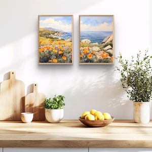 May include: Two framed watercolor paintings depicting a coastal landscape with orange wildflowers in the foreground and a blue ocean in the background.