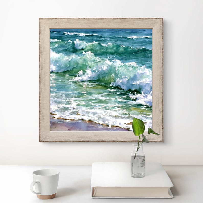 May include: A square framed watercolour painting depicting ocean waves crashing towards a sandy shore. The artwork features shades of deep blue, turquoise, and white sea foam, enclosed in a light-coloured, weathered wooden frame with a textured finish.
