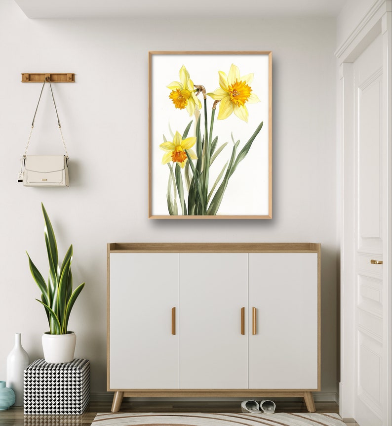 May include: A framed print of a watercolor painting of yellow daffodils with green leaves on a white background.