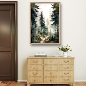 May include: A watercolor painting of a forest path with tall trees on either side. The path leads into the distance, where the trees are obscured by fog. The painting is framed in a light wood frame.