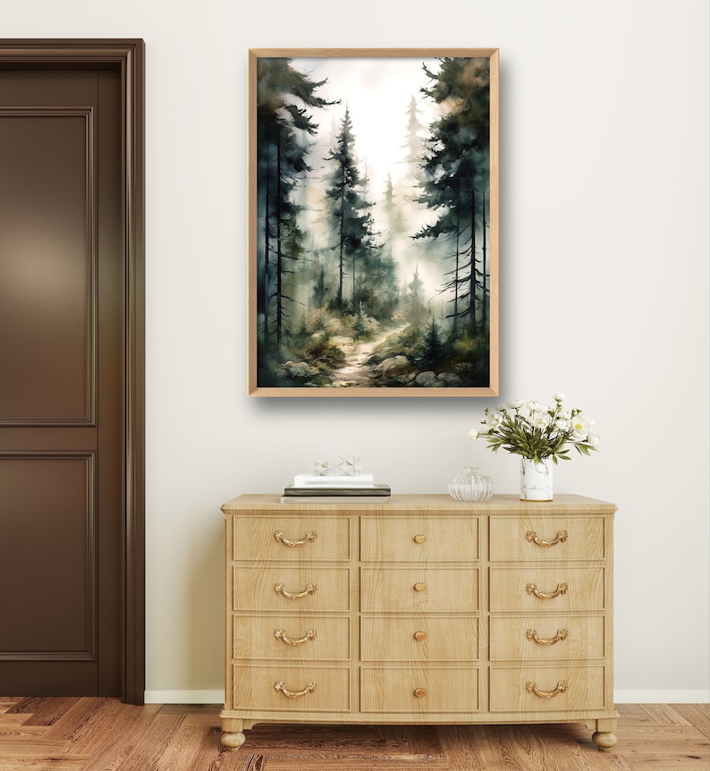 May include: A watercolor painting of a forest path with tall trees on either side. The path leads into the distance, where the trees are obscured by fog. The painting is framed in a light wood frame.