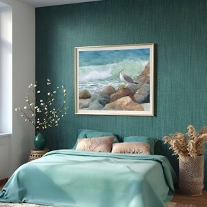 May include: A bedroom with teal walls and bedding. A framed watercolor painting of a seagull on rocks by the ocean hangs above the bed. Decorative items include a vase with flowers, pillows, and a woven basket with dried plants.
