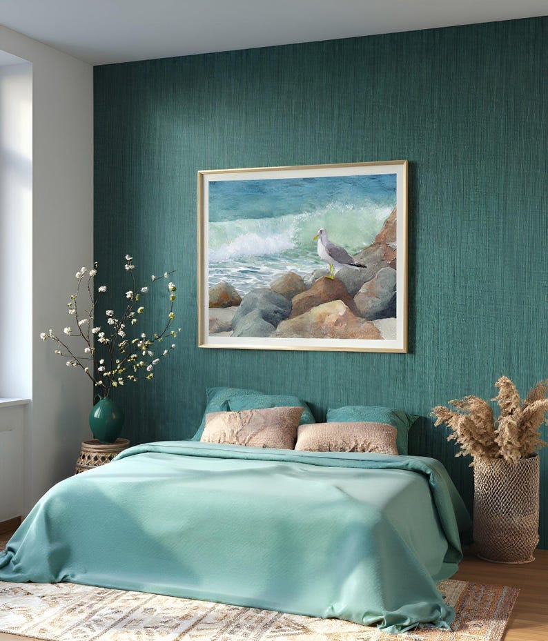 May include: A bedroom with teal walls and bedding. A framed watercolor painting of a seagull on rocks by the ocean hangs above the bed. Decorative items include a vase with flowers, pillows, and a woven basket with dried plants.