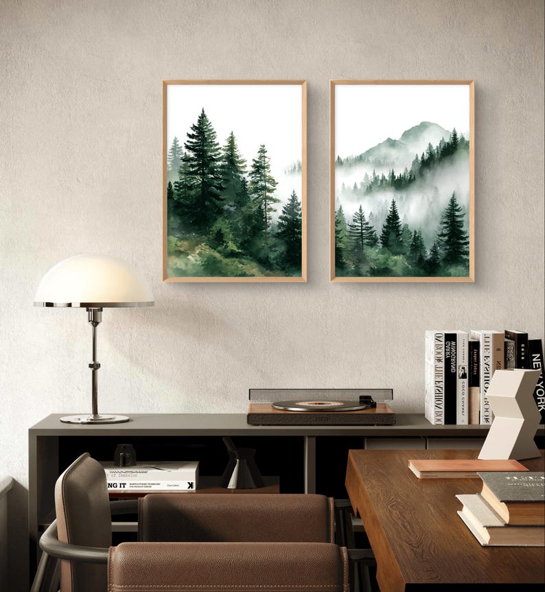 May include: Two framed watercolor prints of forest scenes. One depicts tall evergreen trees, the other a mountain range with trees shrouded in mist. Both are in light wood frames, creating a natural aesthetic.