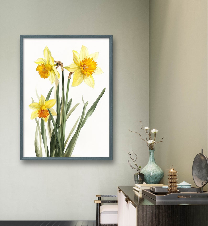 May include: A framed watercolor painting of yellow daffodils with orange centers and green leaves on a white background.