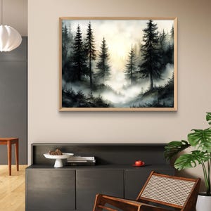 May include: A framed watercolor painting of a misty forest scene. The artwork features tall, dark evergreen trees silhouetted against a bright, hazy sky. The painting is in a natural wood frame and hangs above a dark gray cabinet.