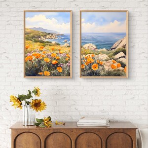 May include: Two framed watercolor paintings of a coastal landscape with orange wildflowers in the foreground and a blue ocean in the background.