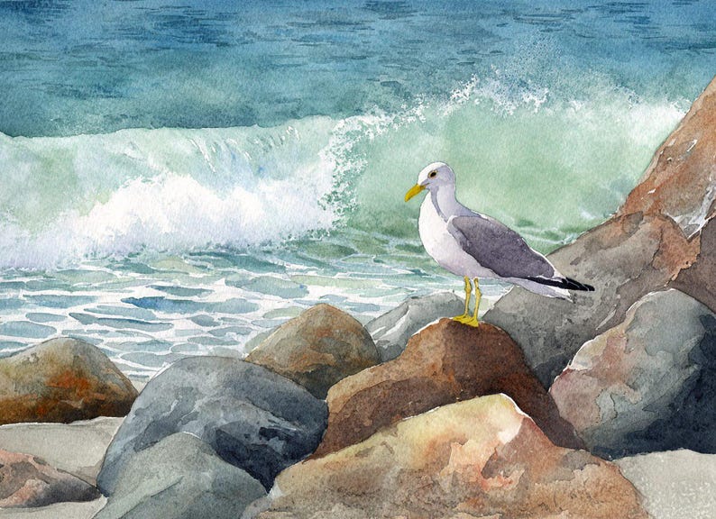 Watercolor painting of a seagull standing on rocks near the ocean. The bird has gray wings, a white body, and a yellow beak and feet. The background features a crashing wave and blue-green water.