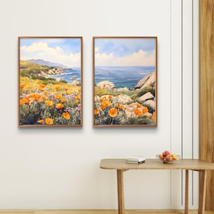 May include: Two framed watercolor paintings depicting a coastal landscape. The left painting shows a field of orange poppies in the foreground with a rocky coastline and blue ocean in the background. The right painting shows a close-up of the rocky coastline with the blue ocean in the background.