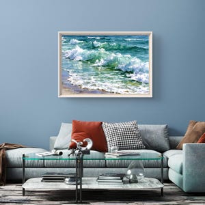 May include: A rectangular wall art print featuring a realistic painting of ocean waves crashing towards a sandy shore. The artwork displays shades of deep blue, turquoise, and white sea foam, enclosed within a simple light-coloured wooden frame.