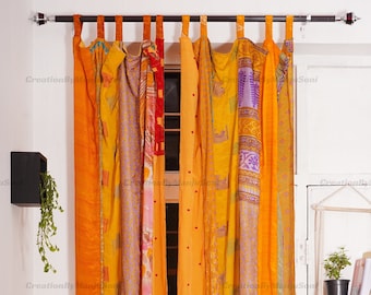 Op de afbeelding: Een set oranje, gele en paarse patchwork gordijnen met een bloemenpatroon. De gordijnen zijn gemaakt van gerecyclede sari's en hangen aan een metalen stang.