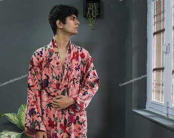 May include: A pink floral print robe with a long sleeve and a sash tie. The robe has a dark green, red, and white floral pattern.