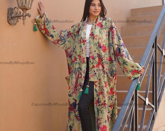 May include: A long, green floral print robe with a shawl collar and tassel accents. The robe is worn over black pants and brown boots.