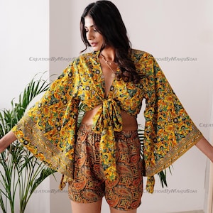 May include: A yellow and green floral print crop top with a tie front and bell sleeves. The top is paired with matching floral print shorts. The shorts have a paisley pattern.