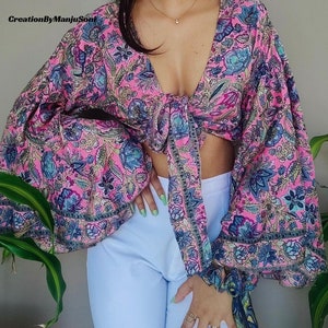 May include: A pink and blue floral print crop top with a tie front and long, puffy sleeves.
