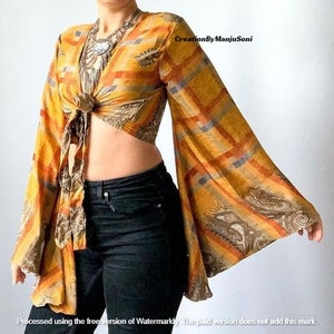 May include: A yellow, orange, and brown patterned crop top with long bell sleeves. The top is tied at the front and has a paisley design.