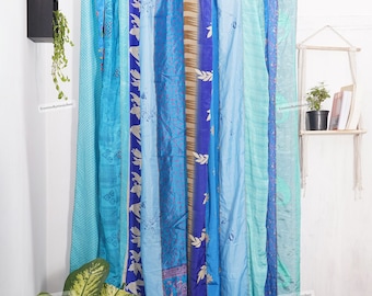 May include: A set of blue and turquoise patterned curtains made from recycled saris. The curtains are hung on a rod and are ready to be used as a room divider or window treatment.