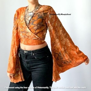 May include: A long-sleeved wrap top with a floral print in shades of orange and brown. The top has a tie closure at the waist and wide bell sleeves. The top is made of a lightweight fabric and is perfect for layering.
