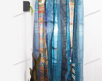 May include: A set of blue and multi-coloured curtains made from recycled saris. The curtains are hung on a rod with orange rings. The curtains have a variety of patterns and designs.
