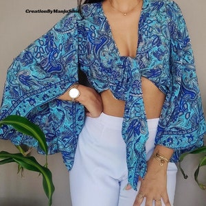 May include: A blue and white paisley print crop top with a tie front and long bell sleeves.