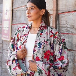 May include: A gray and white floral kimono with red and pink flowers and birds. The kimono has a long sleeve and a tie belt.