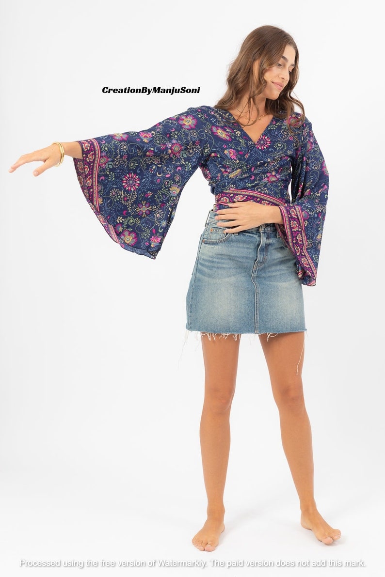 May include: A woman wearing a blue and purple floral print wrap top with long bell sleeves and a denim skirt.