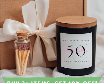 May include: A black candle with a wooden lid and a white label that says "To a special friend 50 Happy Birthday". The candle is sitting on a brown box with a white ribbon.