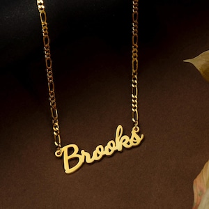 May include: A gold chain necklace with a cursive nameplate pendant that reads "Brooks".